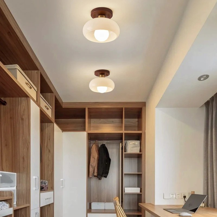 Twee lampen naast elkaar aan het plafond van een inloopkast met houten kasten en werkplek 4