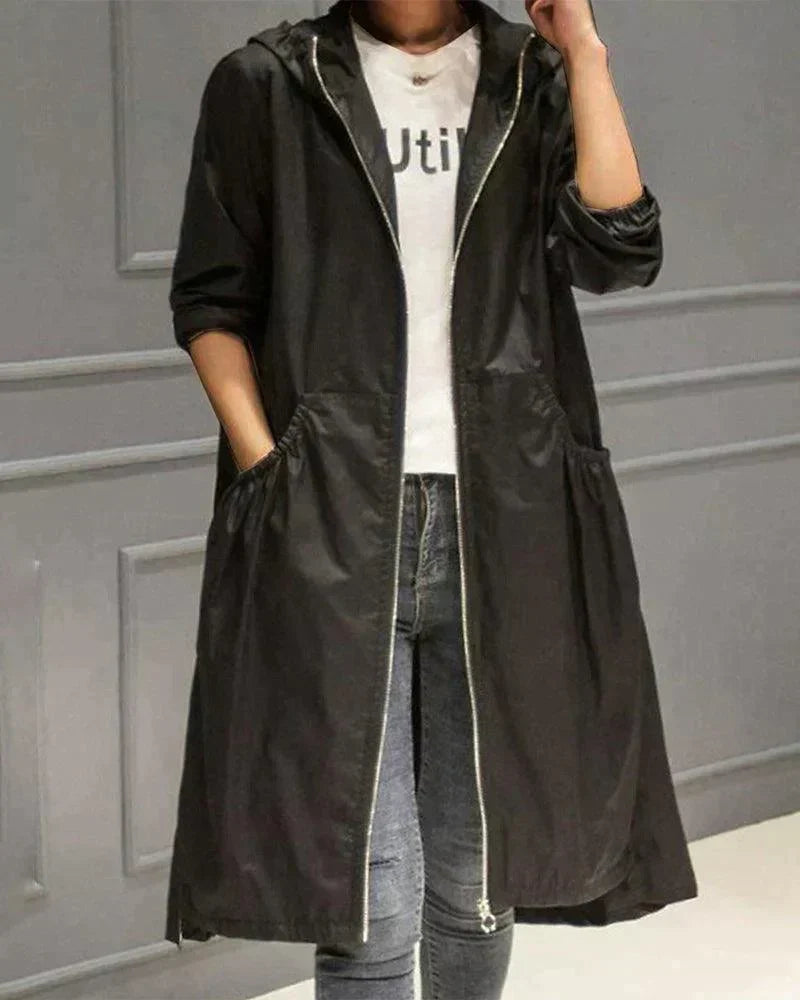 Zwarte lange regenjas met capuchon en rits, open gedragen met jeans, model houdt hand in zak 4