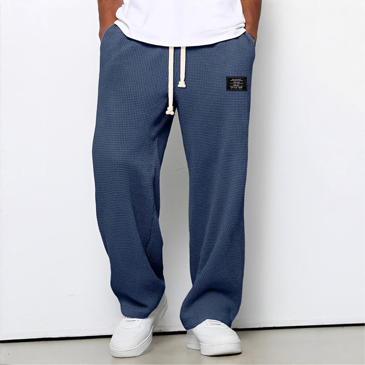 Model draagt de wafelstructuur broek in donkerblauw met witte trekkoord en witte sneakers 5