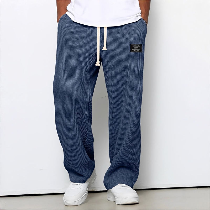 Model draagt de wafelstructuur broek in donkerblauw met witte trekkoord en witte sneakers 5