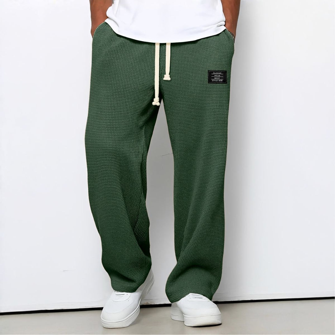 Model draagt de wafelstructuur broek in groen met witte trekkoord en witte sneakers 4