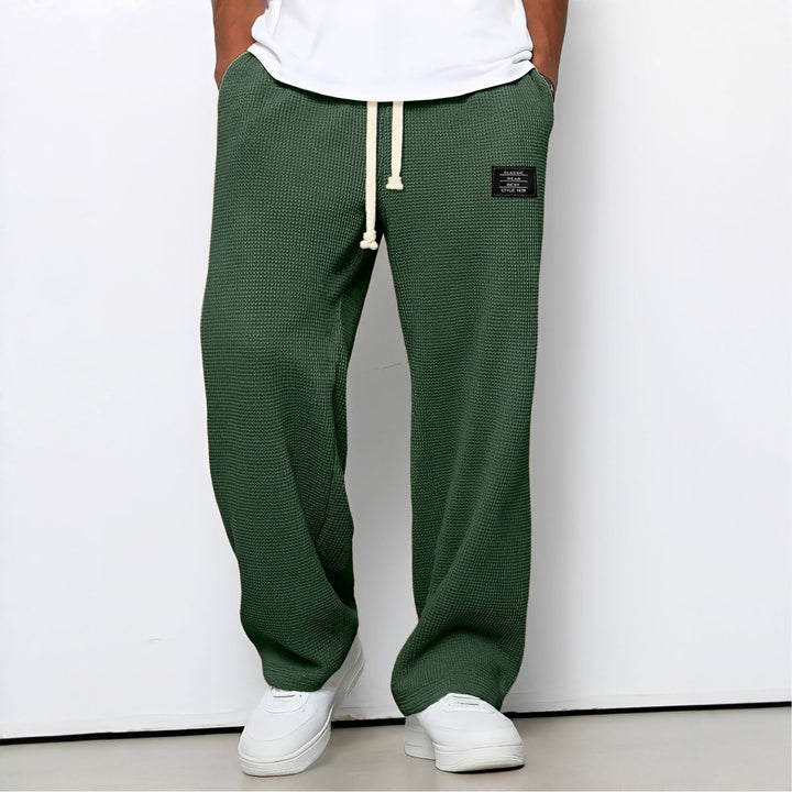 Model draagt de wafelstructuur broek in groen met witte trekkoord en witte sneakers 4