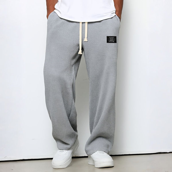 Model draagt de wafelstructuur broek in lichtgrijs met witte trekkoord en witte sneakers 6