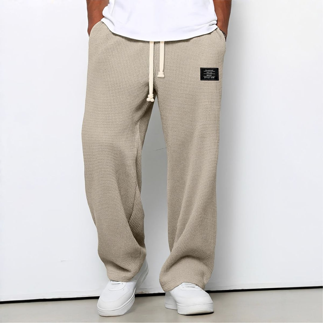 Model draagt de wafelstructuur broek in beige met witte trekkoord en witte sneakers 7