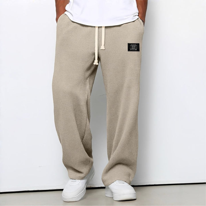 Model draagt de wafelstructuur broek in beige met witte trekkoord en witte sneakers 7