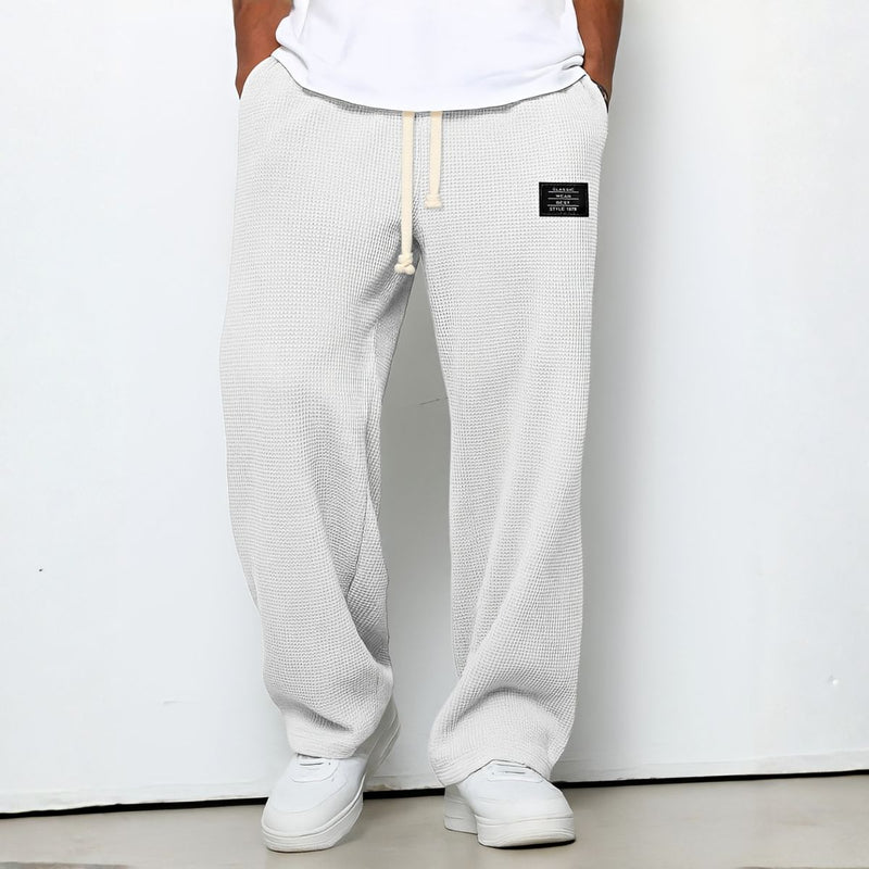 Model draagt de wafelstructuur broek in witte tint met trekkoord en witte sneakers 8