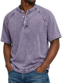 Model draagt het gewassen shirt met knoopsluiting en raglanmouwen in lila, met een hand in de zak van een spijkerbroek. 1