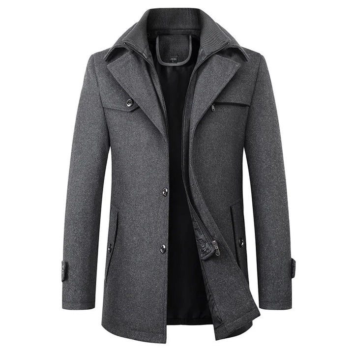 Voorkant van de peacoat in grijs, met zichtbare binnenlaag met ritssluiting, drie knopen, klepzakken en een gebreide opstaande kraag. 2