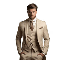 Model draagt het kostuum in beige met fijne streepstructuur, vest met horlogeketting, bruine stropdas en pochet, handen in de broekzakken. 2