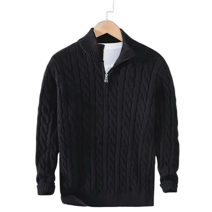 Zwarte kabeltrui met korte rits aan een houten kleerhanger, met een wit shirt zichtbaar onder de opstaande kraag. 2