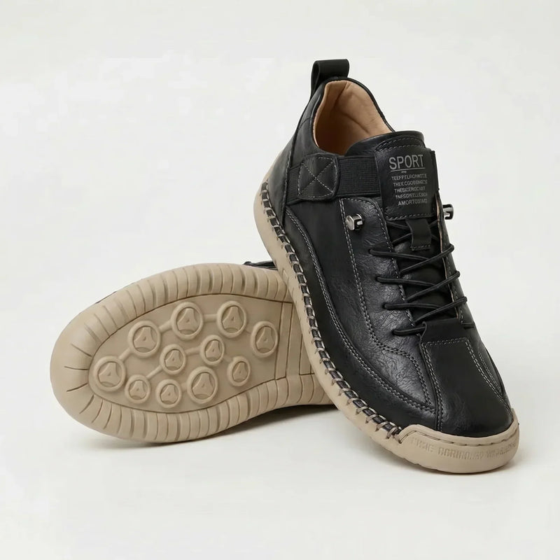Zwarte sneaker met opvallende handgestikte rand en beige zool, met de noppenzool van de tweede schoen in beeld. 12