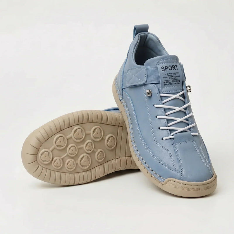 Lichtblauwe sneaker met witte veters en beige zool, schuin gezet naast een schoen met de profielzool zichtbaar. 11
