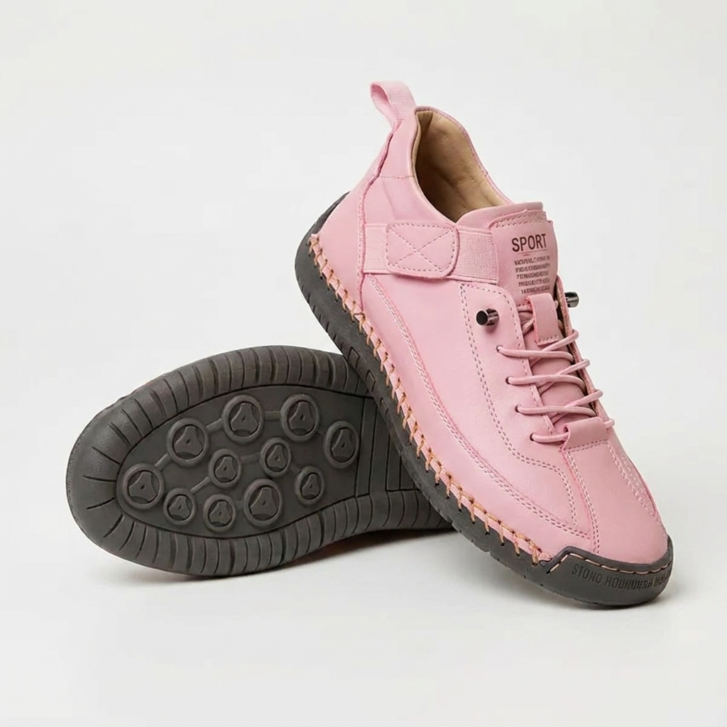 Roze sneaker met oranje stiksels en donkergrijze zool, met de tweede schoen op zijn kant en de zool zichtbaar. 14