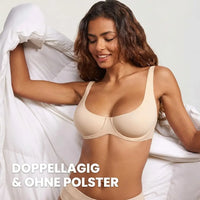 Lachende vrouw in beige bh zonder vulling, met een wit dekbed in haar handen, gefotografeerd van voren. 2