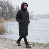 Man draagt de zwarte lange jas met capuchon op zijn hoofd tijdens een wandeling langs een bevroren meer 2