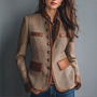 Voorkant van de tweedjas in visgraatpatroon, gedragen met bruine blouse en spijkerbroek, met leren klepzakken, metalen knopen en leren manchetten. 1