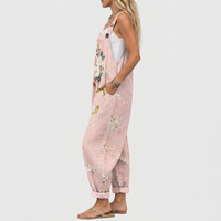 Zijaanzicht: model draagt de roze tuinbroek met bloemenprint, een hand in de zijzak, de ruime pasvorm en omgeslagen pijpen goed zichtbaar. 3