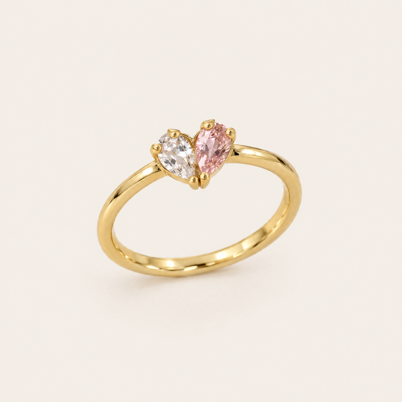 Gouden ring van schuin voren gezien met een helder en een roze druppelvormige steen die samen een hartje vormen. 1