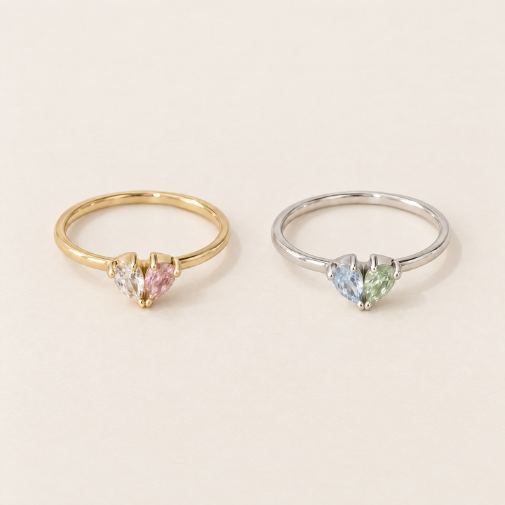 Twee ringen naast elkaar: een gouden met helder en roze stenen en een zilverkleurige met blauwe en groene stenen. 4
