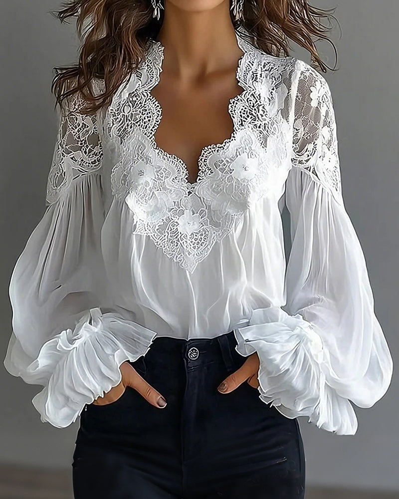 Witte blouse met kanten V-hals en ballonmouwen, handen in de zakken van een zwarte jeans 1