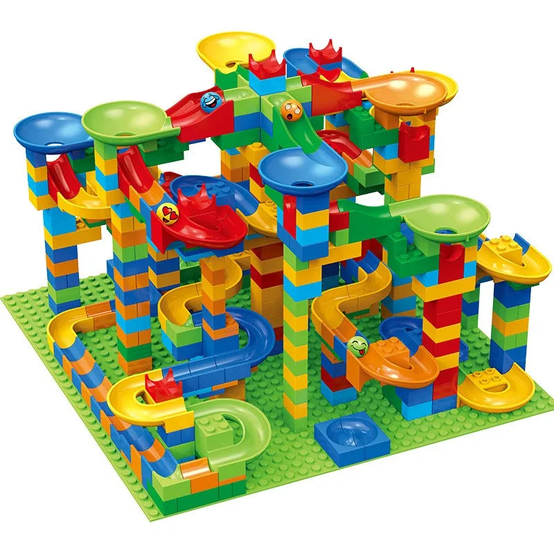 Grote, hoge knikkerbaan in blauw, geel, groen en rood met trechters, glijbanen en bochten op een groene bouwplaat. 2