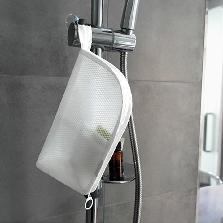 Witte mesh toilettas hangt aan de lus aan de douchestang in een betegelde douche, met flesjes in de buurt. 4