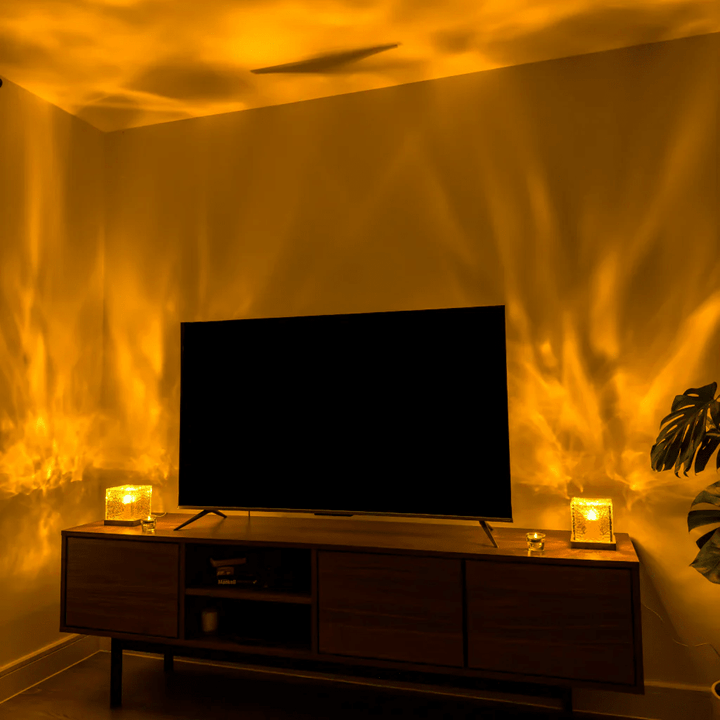 Twee kubuslampen links en rechts op een tv-meubel werpen warm oranje lichtgolven over de woonkamermuren rond de televisie. 4