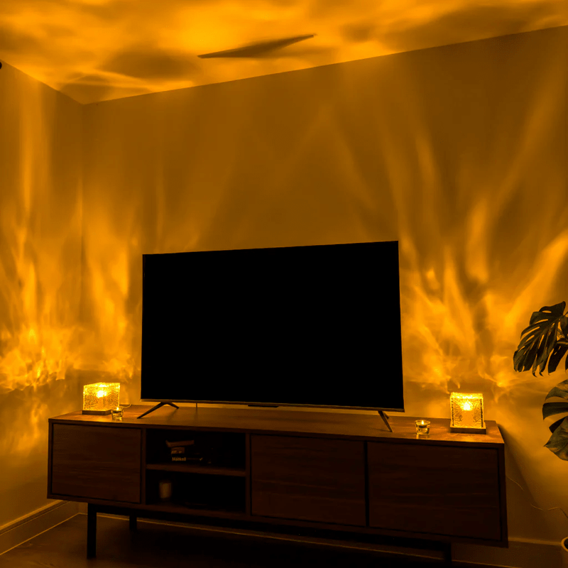 Twee kubuslampen links en rechts op een tv-meubel werpen warm oranje lichtgolven over de woonkamermuren rond de televisie. 4