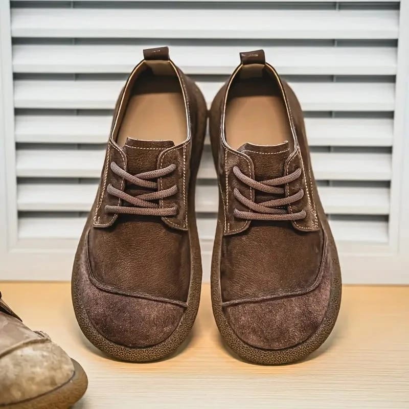 Paar donkerbruine veterschoenen naast elkaar voorop gefotografeerd, voor een lamellenpaneel, met aan de zijkant een lichtere schoen. 6