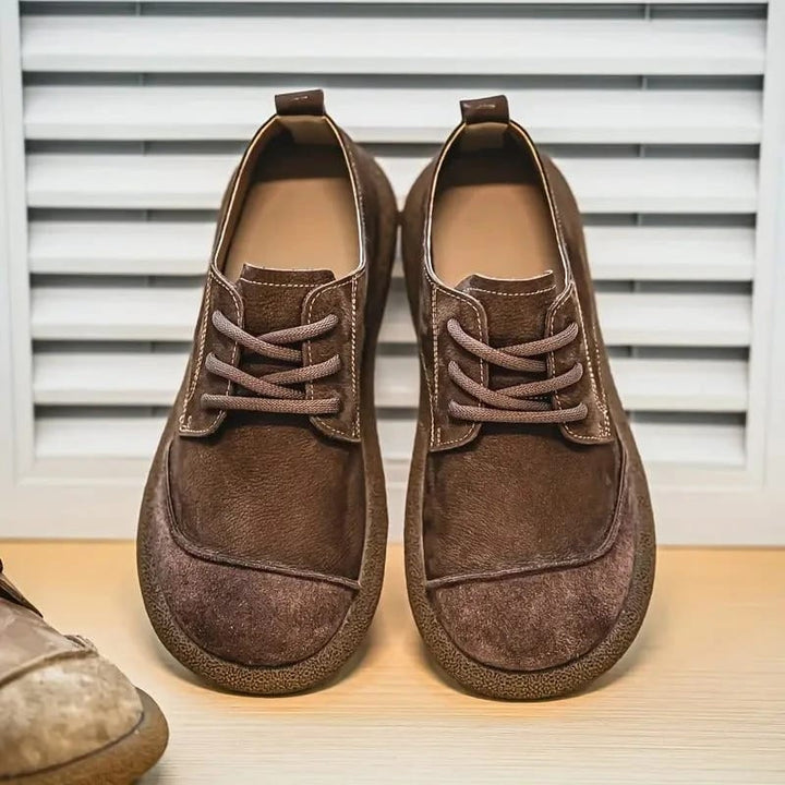 Paar donkerbruine veterschoenen naast elkaar voorop gefotografeerd, voor een lamellenpaneel, met aan de zijkant een lichtere schoen. 6