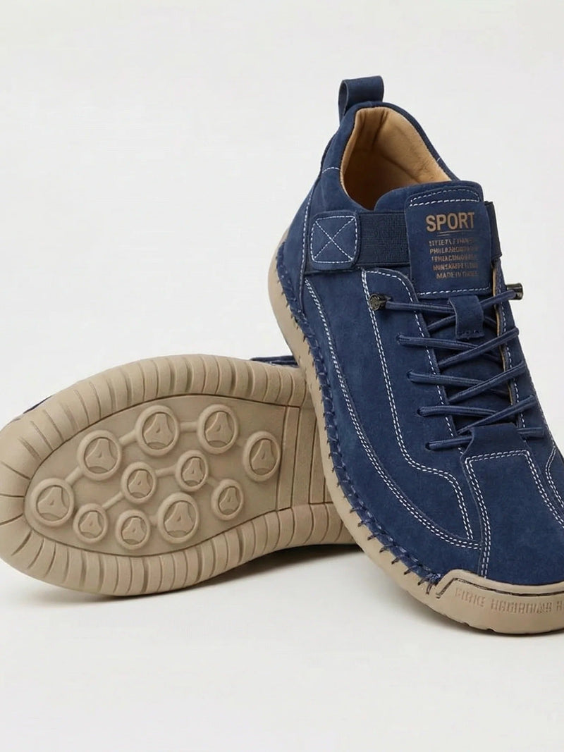 Donkerblauwe suÃ¨de instapper met witte stiksels, naast een schoen met beige zool met noppenprofiel 2