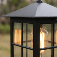 Close-up van het schuine zwarte dak en het raamwerk van de lamp, met een warm brandende lamp erachter. 6