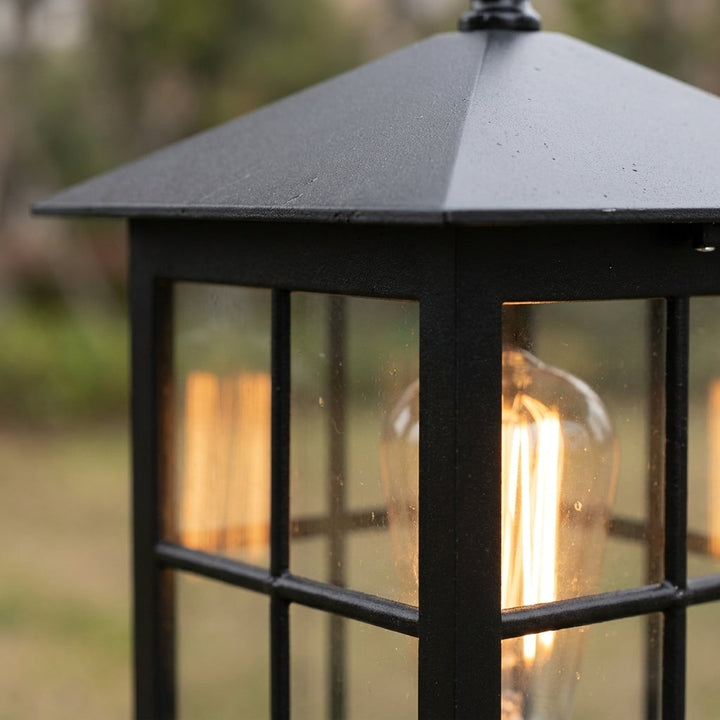 Close-up van het schuine zwarte dak en het raamwerk van de lamp, met een warm brandende lamp erachter. 6