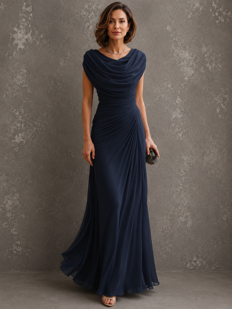 Model in dezelfde jurk in donkerblauw, vooraanzicht met gedrapeerde halslijn en vloerlange rok, clutch in de hand. 2
