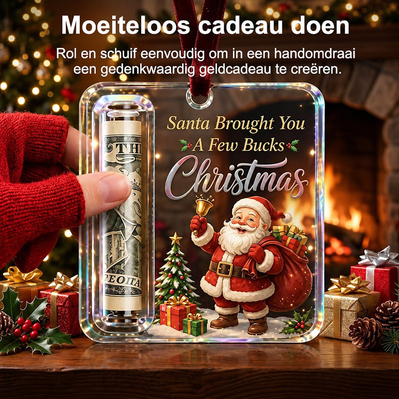 Hand in rode handschoen schuift een opgerold biljet in het buisje van de acryl hanger met kerstman, bij een haardvuur. 2