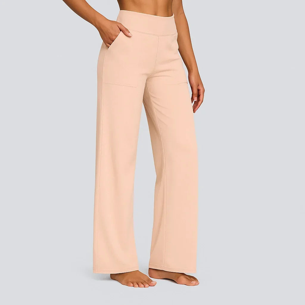 Model in zachte perzikkleurige broek met hoge taille en rechte pijpen, zijaanzicht met hand in de zijzak. 14