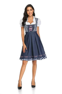 Vooraanzicht van de dirndl met marineblauw schort, blauw-wit geruite ruches en roze veters, gedragen door een lachend model. 3