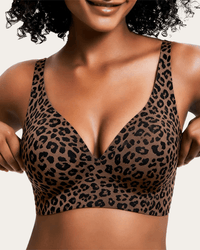 Model draagt de naadloze beha met V-hals in bruin met zwarte luipaardprint, voorkant, terwijl ze de bandjes vasthoudt. 1