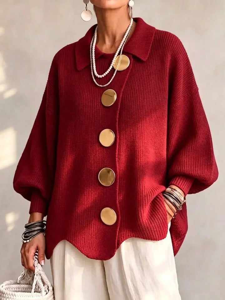 Model draagt het gebreide vest in rood met gouden knopen en een witte broek, vooraanzicht. 11