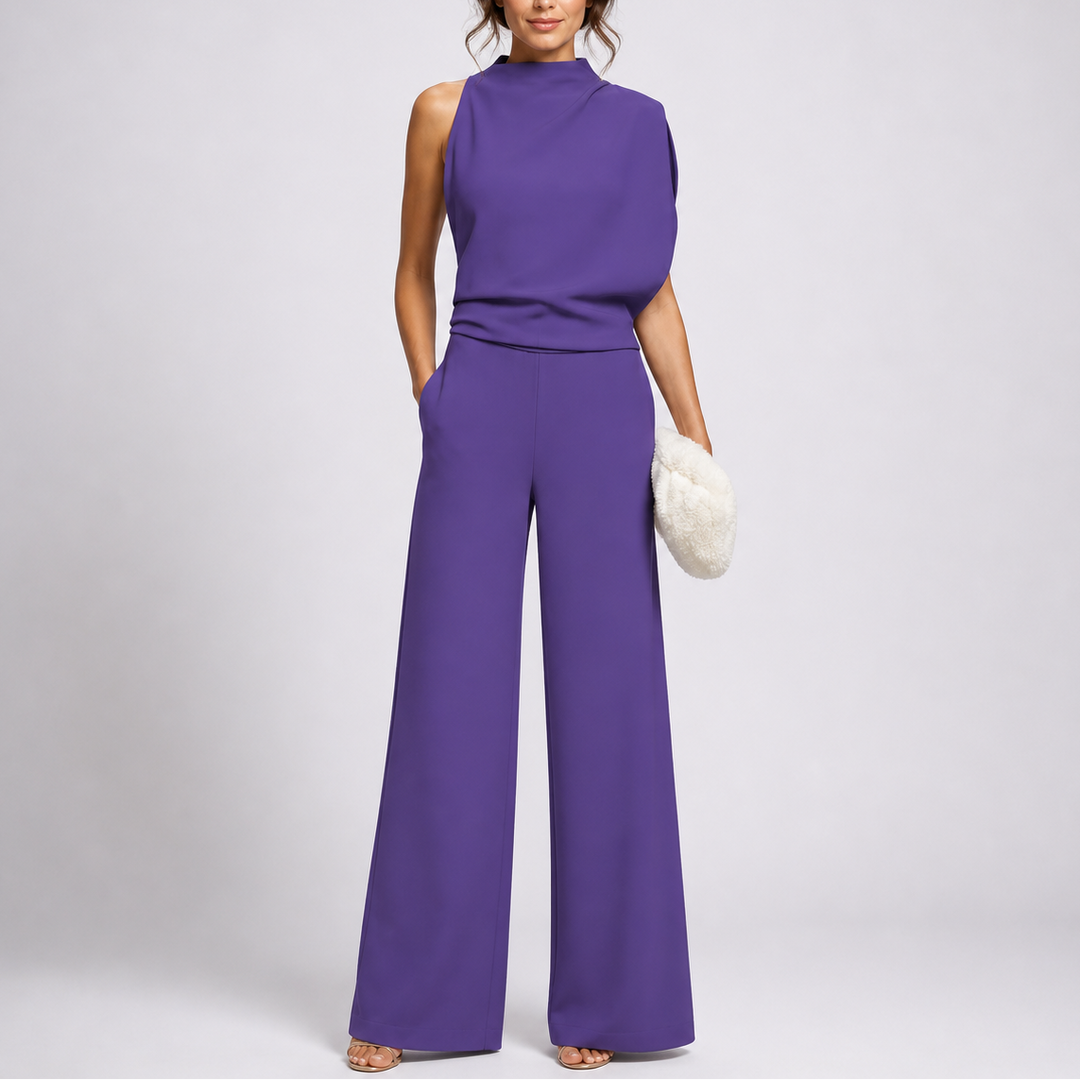 Model draagt de jumpsuit in paars met een asymmetrisch gedrapeerd bovenstuk en sandalen 3