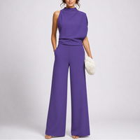 Model draagt de jumpsuit in paars met een asymmetrisch gedrapeerd bovenstuk en sandalen 3