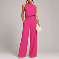 Model draagt de jumpsuit in felroze met hoge hals, zakken en een witte pluchen clutch 4