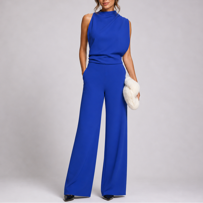 Model draagt de jumpsuit in koningsblauw met gedrapeerd bovenstuk, zwarte pumps en pluchen clutch 6