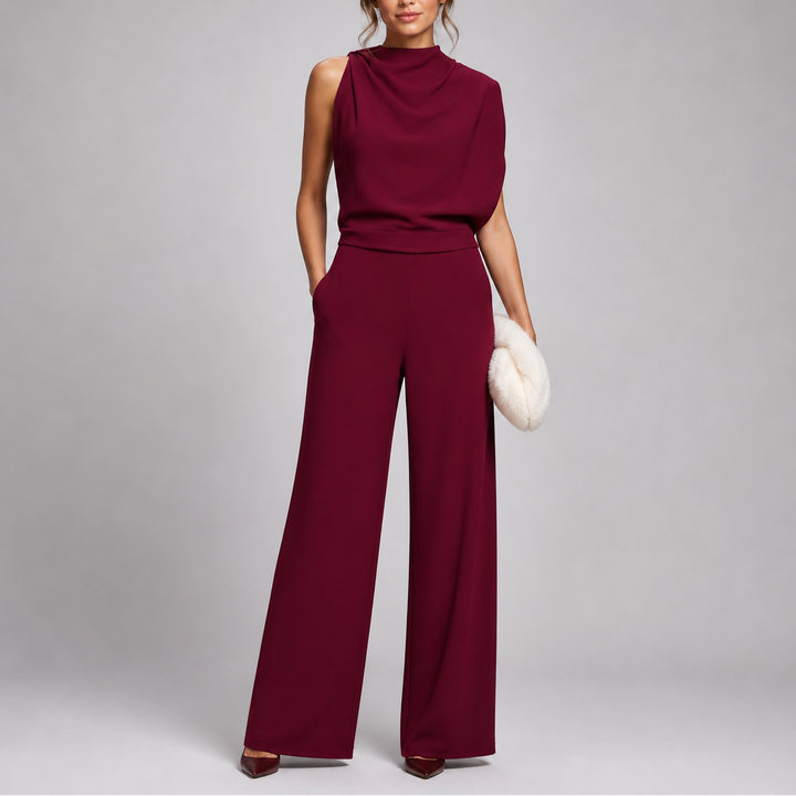 Model draagt de jumpsuit in bordeauxrood met gedrapeerd bovenstuk en wijde pijpen, met pluchen clutch 7