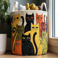 Ronde gewatteerde mand met kleurrijke appliqué-katten en twee stoffen handgrepen, gevuld met knuffelachtig speelgoed, naast een plant en een raam. 1