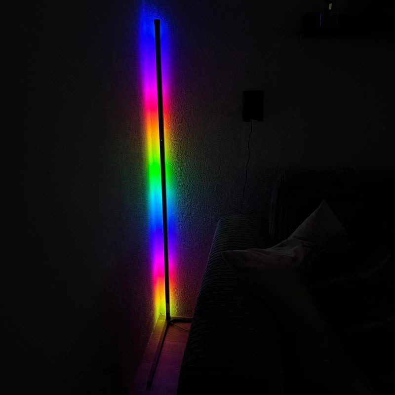 Hoekvloerlamp in een donkere kamer die als regenboog van kleuren op de muur schijnt, met een stopcontact en snoer ernaast. 6