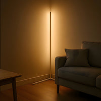 Lichte hoekvloerlamp met warm, indirect licht in een hoek naast een bank met kussen en een houten tafel op de voorgrond. 7