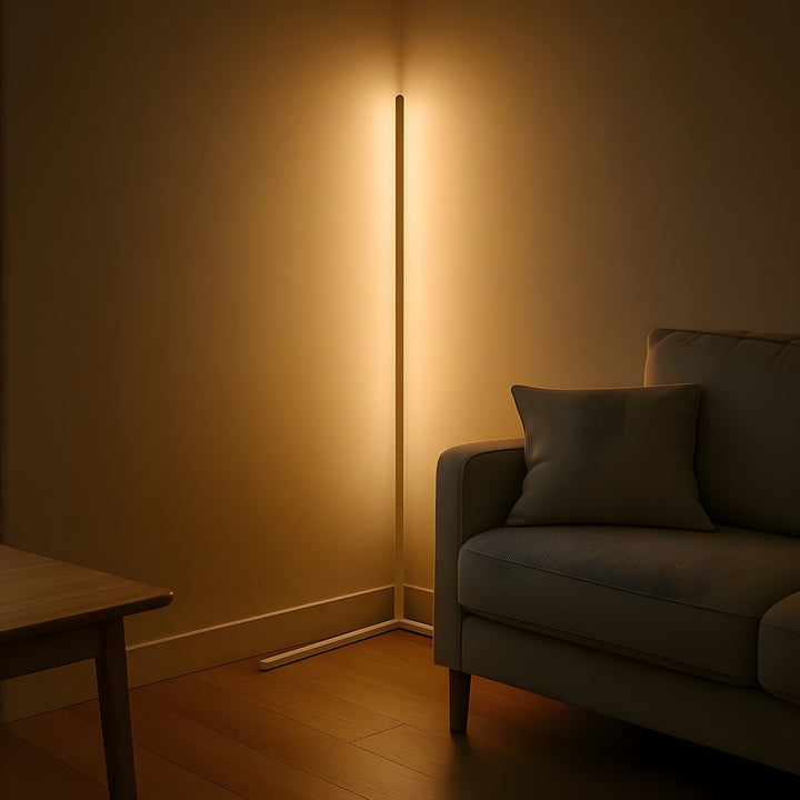 Lichte hoekvloerlamp met warm, indirect licht in een hoek naast een bank met kussen en een houten tafel op de voorgrond. 7