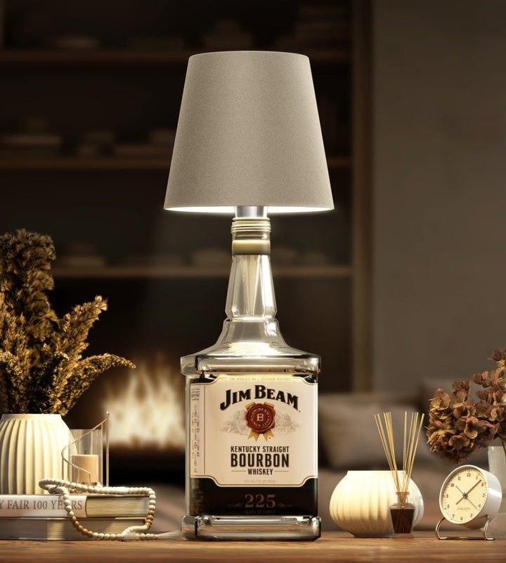 Taupe lampenkap op een vierkante bourbonfles, in een gezellige woonkamer met haardvuur, droogbloemen en een wekker. 8