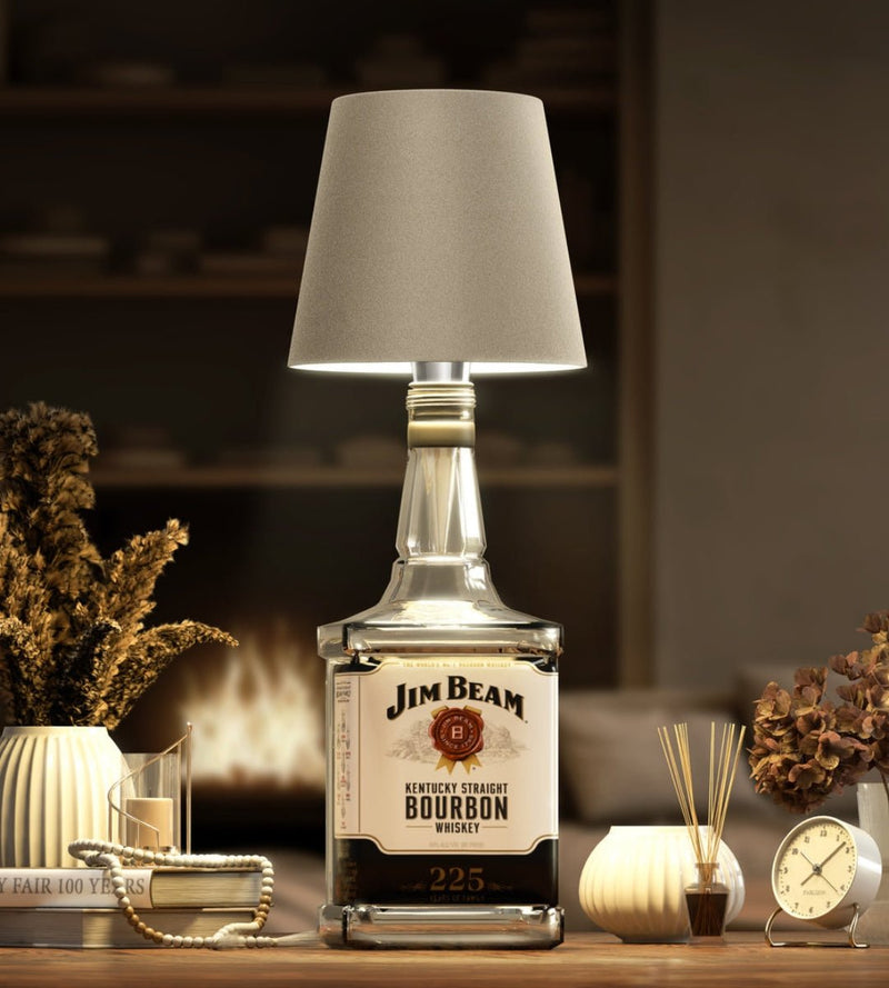 Taupe lampenkap op een vierkante bourbonfles, in een gezellige woonkamer met haardvuur, droogbloemen en een wekker. 8